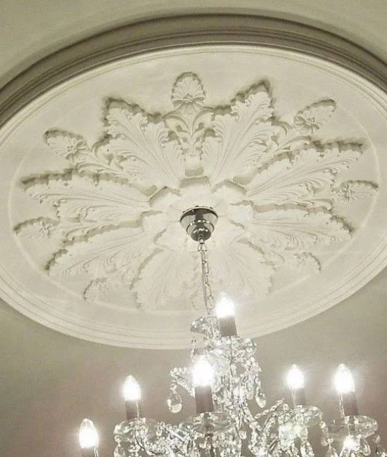 Ornate plaster ceiling rose with a crystal chandelier hanging from the centre, illuminating the room — classic design — Glasgow