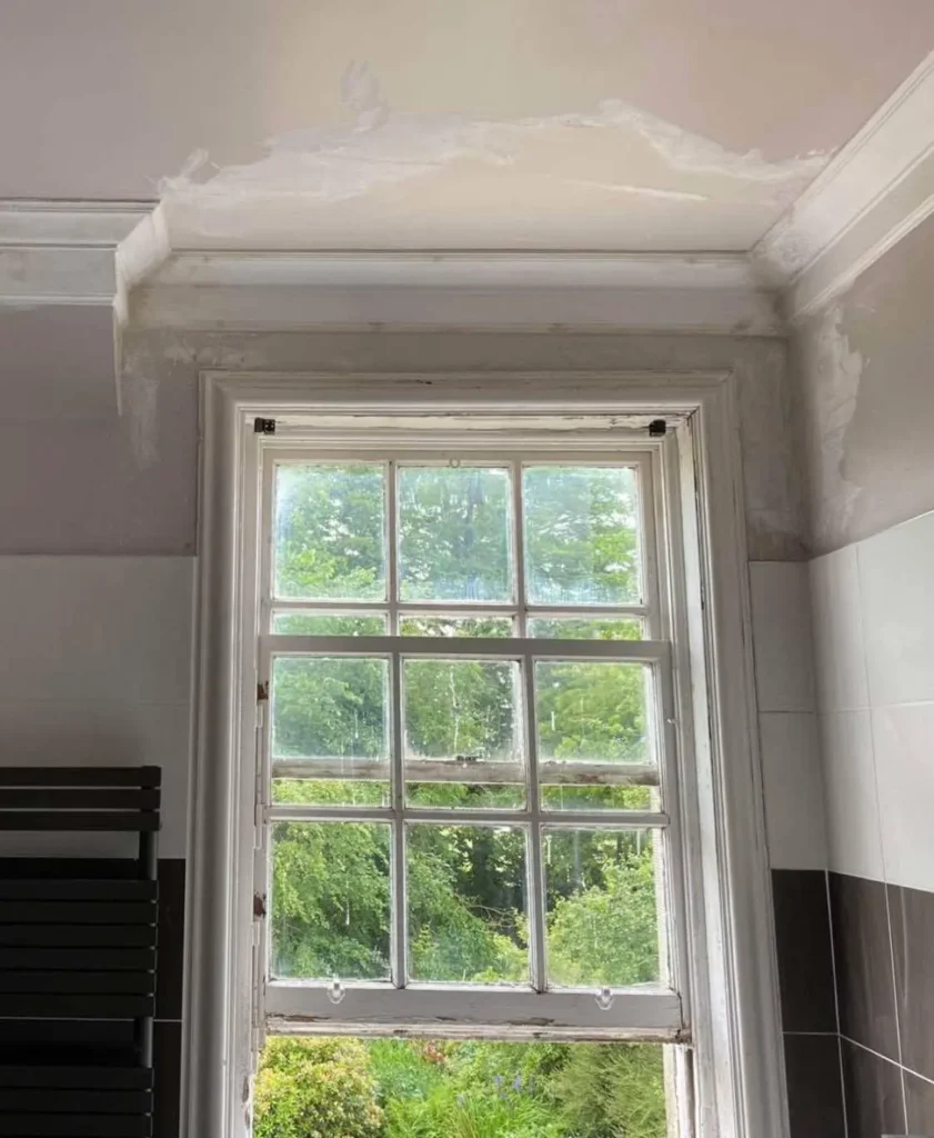 Damaged ceiling above sash window with visible stains and peeling plaster – water damaged ceiling, Glasgow