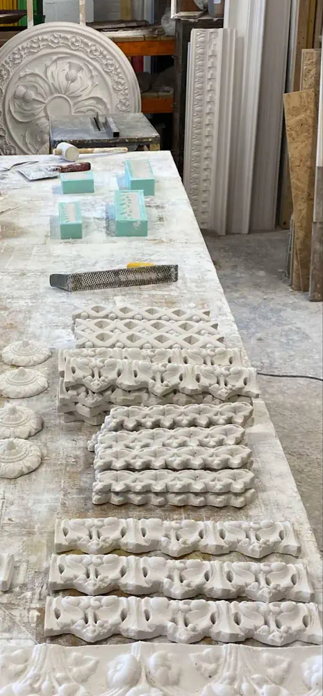 Restoration table with plaster cornice mouldings, ceiling rose casts, and sculpting tools – Cornice repairs – Glasgow